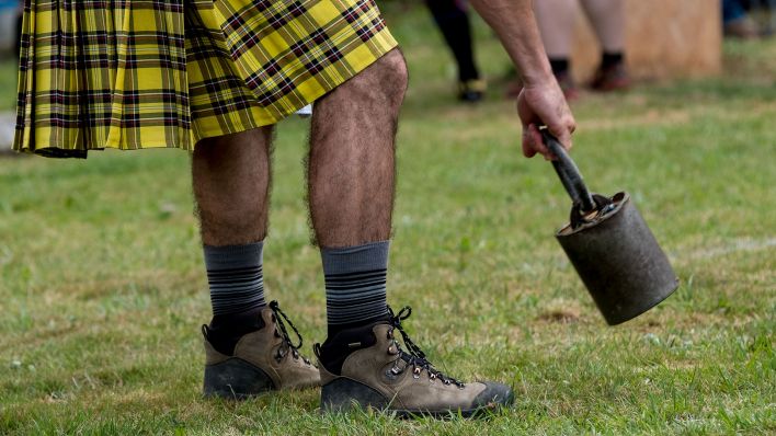 Teilnehmer der Highland Games hebt Gewicht vom Boden auf (Bild: picture alliance/dpa/Peter Steffen)