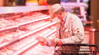 Ein Kunde mit Mund-Nasen-Schutz kauft abgepacktes Fleisch in einem Supermarkt ein. (Quelle: dpa/R.Vennenbernd)