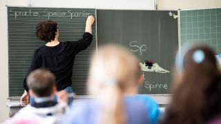 Eine Lehrerin schreibt in einer Grundschule Wörter an eine Tafel. (Quelle: dpa/Sebastian Gollnow)