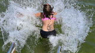 Ein Mädchen rutscht am Strandbad in das Wasser. (Quelle: dpa/Patrick Pleul)