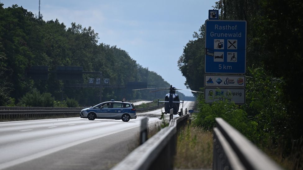Ein Polizeiwagen und ein Hubschrauber stehen in der Nähe der Brandstelle auf der AVUS, der A115. (Quelle: dpa/B. Pedersen)