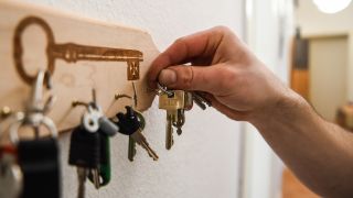 Symbolbild: Ein Mann hängt einen Schlüsselbund an einen Haken am Schlüsselbrett an. (Quelle: dpa/K. Hoffmann)