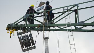 ARCHIV - In circa 60 Metern Höhe klettern zwei Arbeiter auf den Streben eines neuen Strommasten unweit vom brandenburgischen Bernau (Brandenburg). Foto: Patrick Pleul/dpa