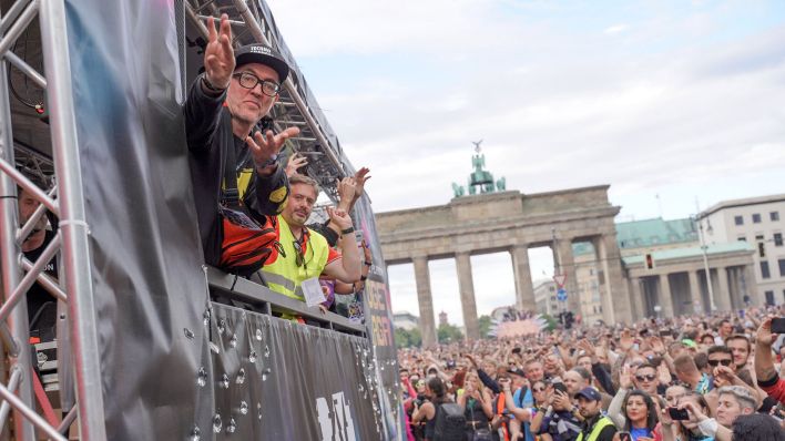 DJ Dr. Motte (l.) zieht bei der von ihm initiierten Techno-Parade «Rave the Planet» auf seinem Wagen am Brandenburger Tor vorbei. (Quelle: dpa/Jörg Carstensen)