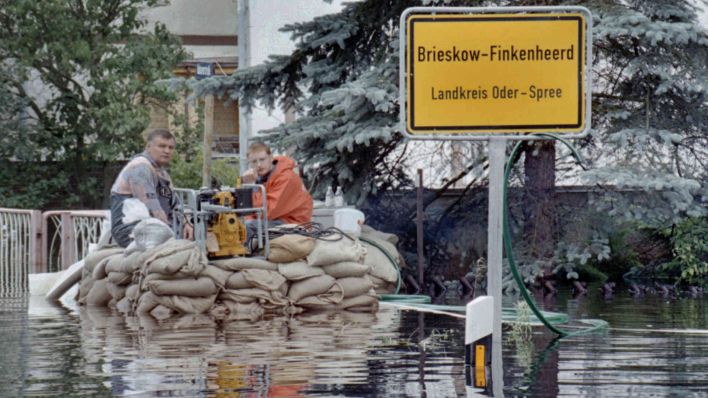 Anwohner eines überfluteten Hauses sitzen in Brieskow-Finkenheerd auf Sandsaecken.(Foto: Jochen Eckel via www.imago-images.de)