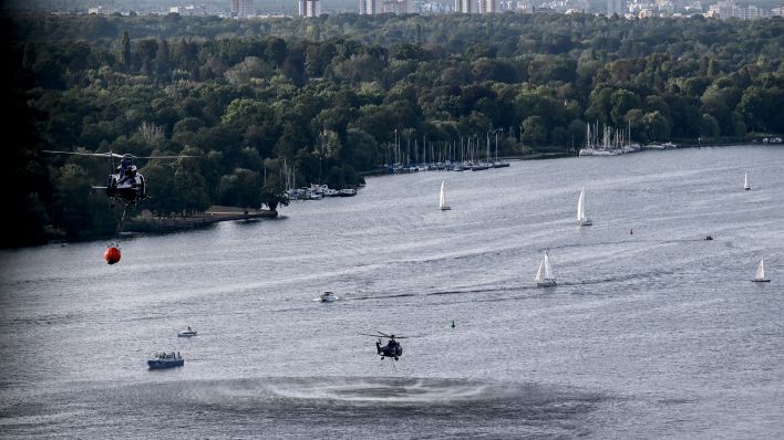 Zwei Hubschrauber der Bundespolizei nehmen am 09.08.2022 aus der Havel Wasser auf, um es über der Brandstelle im Grunewald abzulassen (Quelle: dpa/Britta Pedersen)