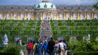 Zahlreiche Besucher spazieren am 16.07.2022 bei sonnigem Wetter im Park Sanssouci auf das Schloss zu. (Quelle: dpa/Monika Skolimowska)