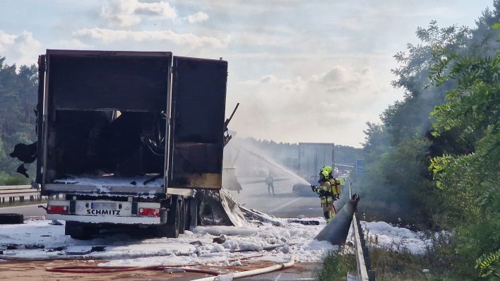 Feuerwehrleute löschen einen brennenden Lastwagen am 09.08.22 auf der A2 bei Wollin (Quelle:dpa-Zentralbild/Cevin Dettlaff)