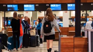 Reisende stehen am Flughafen BER am frühen Morgen an einem Check-In-Schalter. (Quelle: dpa/P.Zinken)