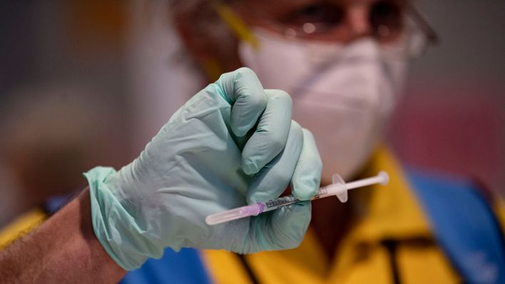 Ein Mitarbeiter des Corona-Impfzentrums hält eine Spritze mit dem Corona-Impfstoff in der Hand. (Quelle: dpa/Fabian Sommer)