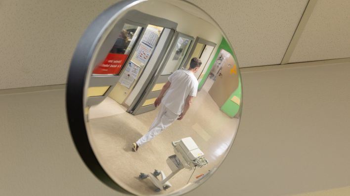 Ein Krankenpfleger ist in einem Spiegel in der Notaufnahme von einem Krankenhaus zu sehen. (Quelle: dpa/Friso Gentsch)