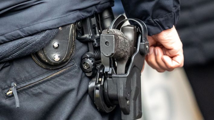 Symbolbild: Nahaufnahme einer Pistole eines Polizisten neben Handschellen und Schlagstock. (Quelle: dpa/Pressefoto Gora)