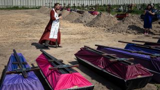 Andrii, orthodoxer Priester, segnet die Särge nicht identifizierter Zivilisten, die während der russischen Besatzung getötet wurden. Mehrere nicht identifizierte Leichen, die aus einem Massengrab exhumiert worden waren, wurden beigesetzt. (Quelle: dpa/Evgeniy Maloletka)