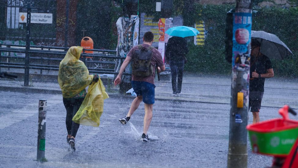 Fußgänger laufen bei starkem Regen durch die Stadt. Nach schweren Regenfällen und Gewittern in Berlin sind größere Schäden etwa durch vollgelaufene Keller weitgehend ausgeblieben. (Quelle: dpa/Annette Riedl)