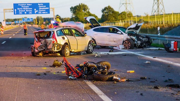 Ein zerstörtes Motorrad und zwei völlig demolierte Autos stehen nach einem schweren Unfall auf der Autobahn 10. (Quelle: dpa/Philipp Neumann)