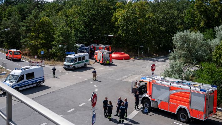 Feuerwehrautos und Fahrzeuge der Polizei stehen in der Nähe der Brandstelle am Grunewald (Bild: dpa/Christophe Gateau)