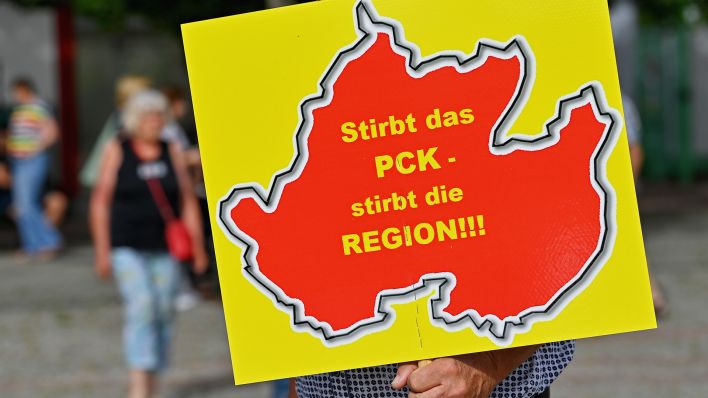 Ein Mann trägt ein Schild mit der Aufschrift «Stirbt das PCK - stirbt die Region!!!» auf einer Demonstration.(Quelle:dpa/P.Pleul)
