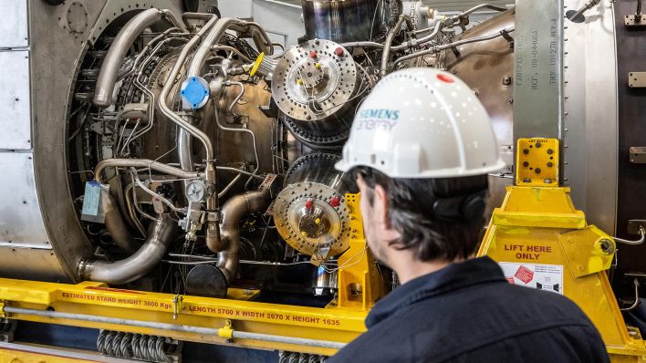 Archivbild: Ein Siemensmitarbeiter steht vor einer Turbine. (Quelle: dpa/B. Thissen)