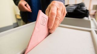 Ein Mann wirft seinen Stimmzettel in eine Urne. (Quelle: dpa/Julian Stratenschulte)