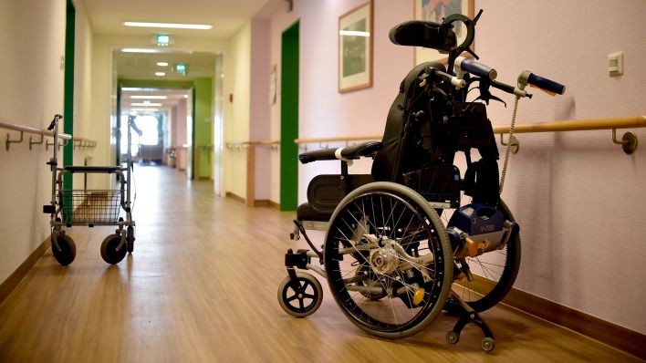 Symbolbild: Ein Rollator und ein Rollstuhl stehen in einer Pflegeeinrichtung auf dem Flur. (Quelle: dpa/Britta Pedersen)