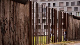 Eine Besucherin geht zwischen den Steelen an der ehemaligen Grenzmauer auf das Gelände der Gedenkstätte Berliner Mauer Bernauer Straße. (Archivbild: Paul Zinken/dpa)