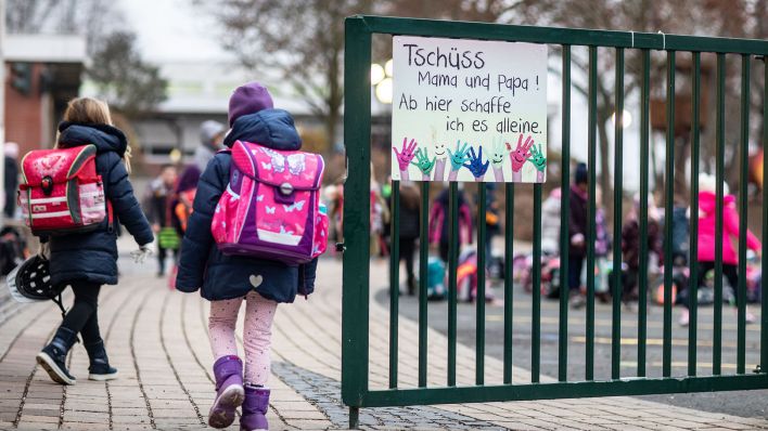 Grundschüler gehen morgens auf den Schulhof vorbei an einem Schild mit der Aufschrift "Tschüss Mama und Papa! Ab hier schaffe ich es alleine." (Quelle: dpa/Frank Rumpenhorst)