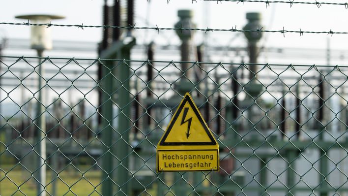 Ein Schild mit der Aufschrift "Hochspannung Lebensgefahr" hängt an einem Zaun. (Quelle: dpa/Sebastian Kahnert)