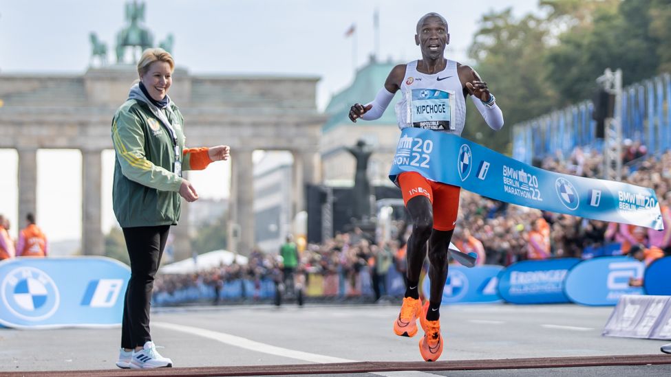 Eliud Kipchoge läuft beim BMW Berlin Marathon nach 2:01:09 Stunden als Erster durchs Ziel und somit einen Weltrekord. Links steht Franziska Giffey (SPD), Berlins Regierende Bürgermeisterin. (Quelle: dpa/A. Gora)