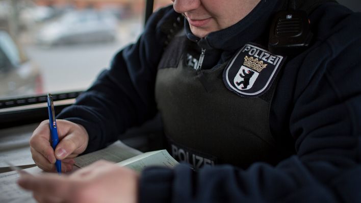 Symbolbild: Ein Polizeibeamter notiert die Personalien. (Quelle: dpa/F. Gaertner)