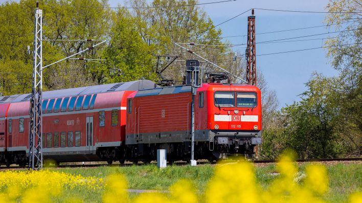Symbolbild: Ein Zug der DB (Deutschen Bahn) fährt an einem Rapsfeld bei Drebkau in der Lausitz vorbei. (Quelle: dpa/A. Franke)