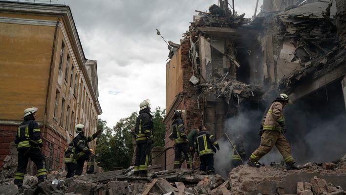 Archivbild: Rettungskräfte arbeiten an einem Gebäude, dass durch Beschuss des russischen Militärs schwer beschädigt wurde. (Quelle: dpa/L. Correa)