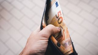 Symbolbild: Ein Mann hält einen Geldbeutel (Quelle: IMAGO/Michael Bihlmayer)