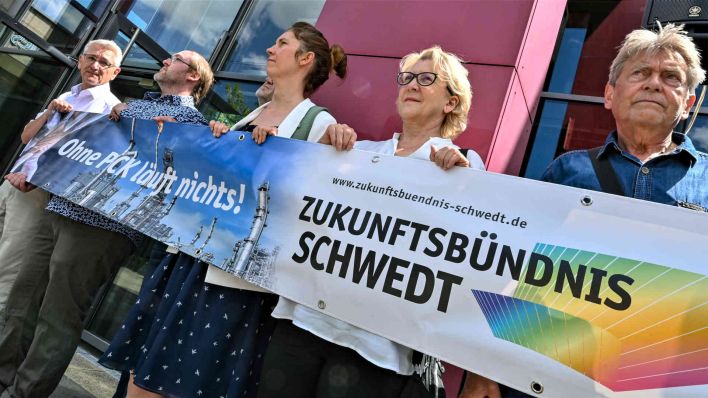 Mitgliedern vom «Zukunftsbündnis Schwedt», halten ein Transparent mit der Aufschrift "Ohne uns läuft nichts". (Foto: Patrick Pleul/dpa)