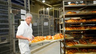 Ein Mitarbeiter der österreichischen Großbäckerei Therese Moelk zieht ein Backblech hervor (Quelle: dpa / Roland Mühlanger).