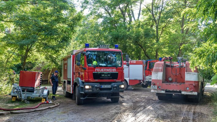 Ein Fahrzeug der Feuerwehr fährt in der Nähe des Einsatzortes durch den Wald. An dieser Stelle hat es Löschwasser aus einem Brunnen aufgenommen. (Quelle: dpa/Frank Hammerschmidt)