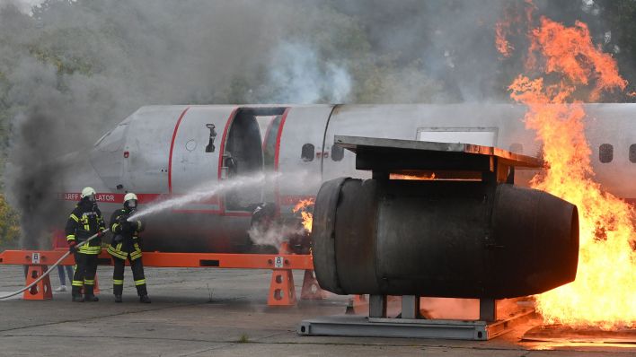 Feuewehrleute löschen am 22.10.2022 ein Triebwerk neben dem Rumpf der Nachbildung eines Airbus A 320 bei einen Katastrophenschutzübung auf dem Flugplatz (Quelle: dpa/Bernd Settnik)