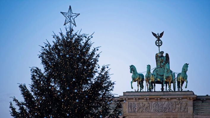 Symbolbild:Hinter einem geschmückten Weihnachtsbaum steht das Brandenburger Tor am Weihnachtstag.(Quelle:dpa/C.Gateau)