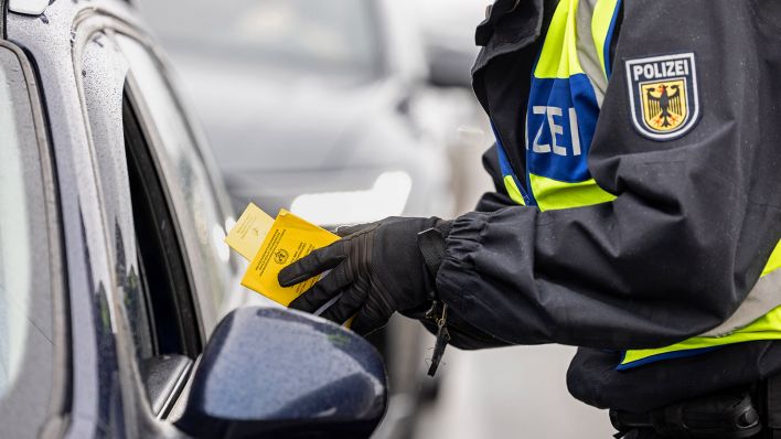 Symbolbild:Ein Bundespolizist kontrolliert Personalien an einem Auto.(Quelle:dpa/M.Balk)