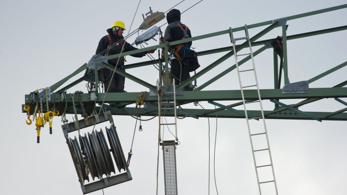 Archivbild: In circa 60 Metern Höhe klettern zwei Arbeiter auf den Streben eines neuen Strommasten unweit vom brandenburgischen Bernau (Brandenburg). (Quelle: Patrick Pleul/dpa)