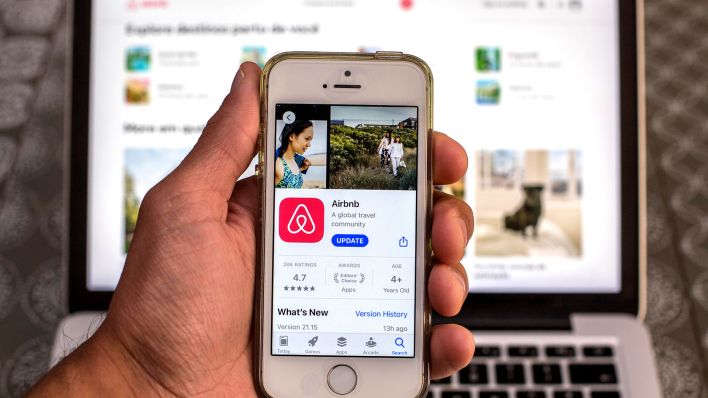 Symbolbild: Die Airbnb-App wird vor einem Laptop auf einem Smartphone präsentiert. (Quelle: dpa/Zuma)