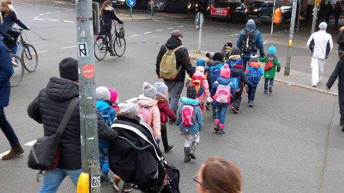Erzieher gehen in Berlin in Steglitz mit Kindern aus einer Kita über eine Ampelkreuzung. (Quelle: dpa/Wolfram Steinberg)