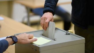 Ein Wähler wirft im Wahllokal seinen Stimmzettel in eine Wahlurne. (Quelle: dpa/Robert Michael)