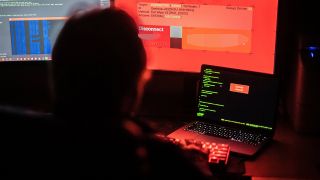 Symbolbild: Ein Mann sitzt vor Bildschirmen, die Hacker-Programme und eine fiktive Fernlösch-Software zeigen. (Quelle: dpa/L. Mirgeler)