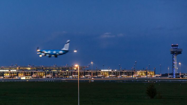 Archivbild: Ein Flugzeug landet nachts auf dem Flughafen Berlin Schoenefeld. Im Hintergrund sieht man den Tower und das Terminal des neuen Flughafen Berlin Brandenburg Willy Brandt. (Quelle: dpa/T. Trutschel)