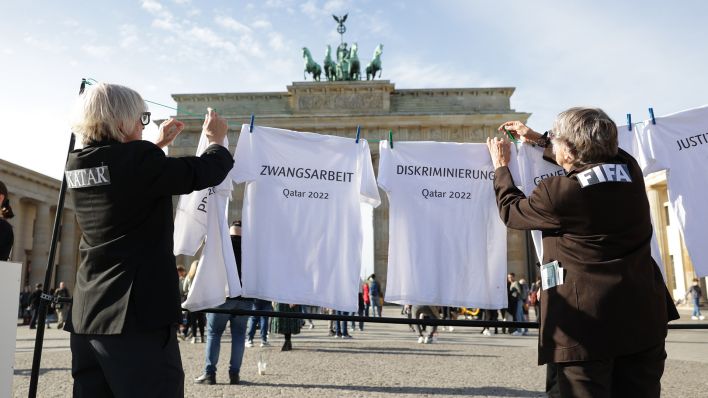 Bei einer Kunstaktion von Amnesty International hängen Schauspieler T-Shirts, auf denen Begriffe wie Pressezensur, Zwangsarbeit, Diskriminierung, Gewerkschaftsverbot und Justizwillkür stehen, an eine Wäscheleine vor dem Brandenburger Tor. (Quelle: dpa/J. Carstensen)