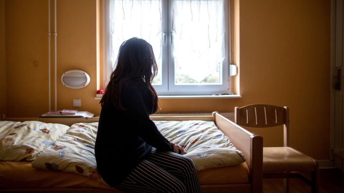 Archivbild: Eine Frau sitzt am 12.11.2015 in einem Frauenhaus auf einem Bett. Frauenhäuser bieten Schutz, wenn der Partner zur Gefahr wird. (Quelle: dpa/Maja Hitij)