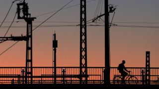 Symbolbild: Ein Radfahrer hebt sich am 08.11.2014 auf einer Brücke in Potsdam (Brandenburg) neben Anlagen der Bahn als Schattenriss vor dem abendlichen Himmel ab. (Quelle: dpa/Ralf Hirschberger)