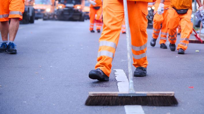 Mitarbeiter der Berliner Stadtreinigung (BSR) und Putzfahrzeuge reinigen die Straße.(Quelle:dpa/A.Riedl)