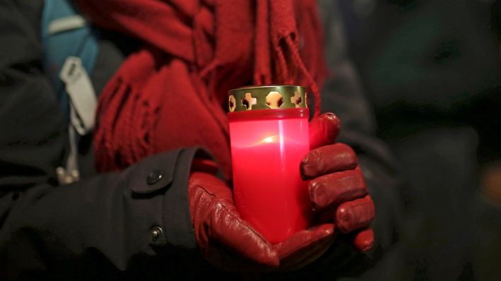 Symbolbild:Eine Person hält eine Grabkerze zum Gedenken an Opfer in den Händen.(Quelle:dpa/Geisler-Fotopress)
