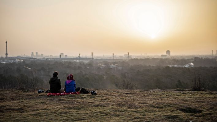 Symbolbild:Zwei Personen zeichnen sich vor der aufgehenden Sonne ab in Berlin.(Quelle:dpa/F.Gaertner)